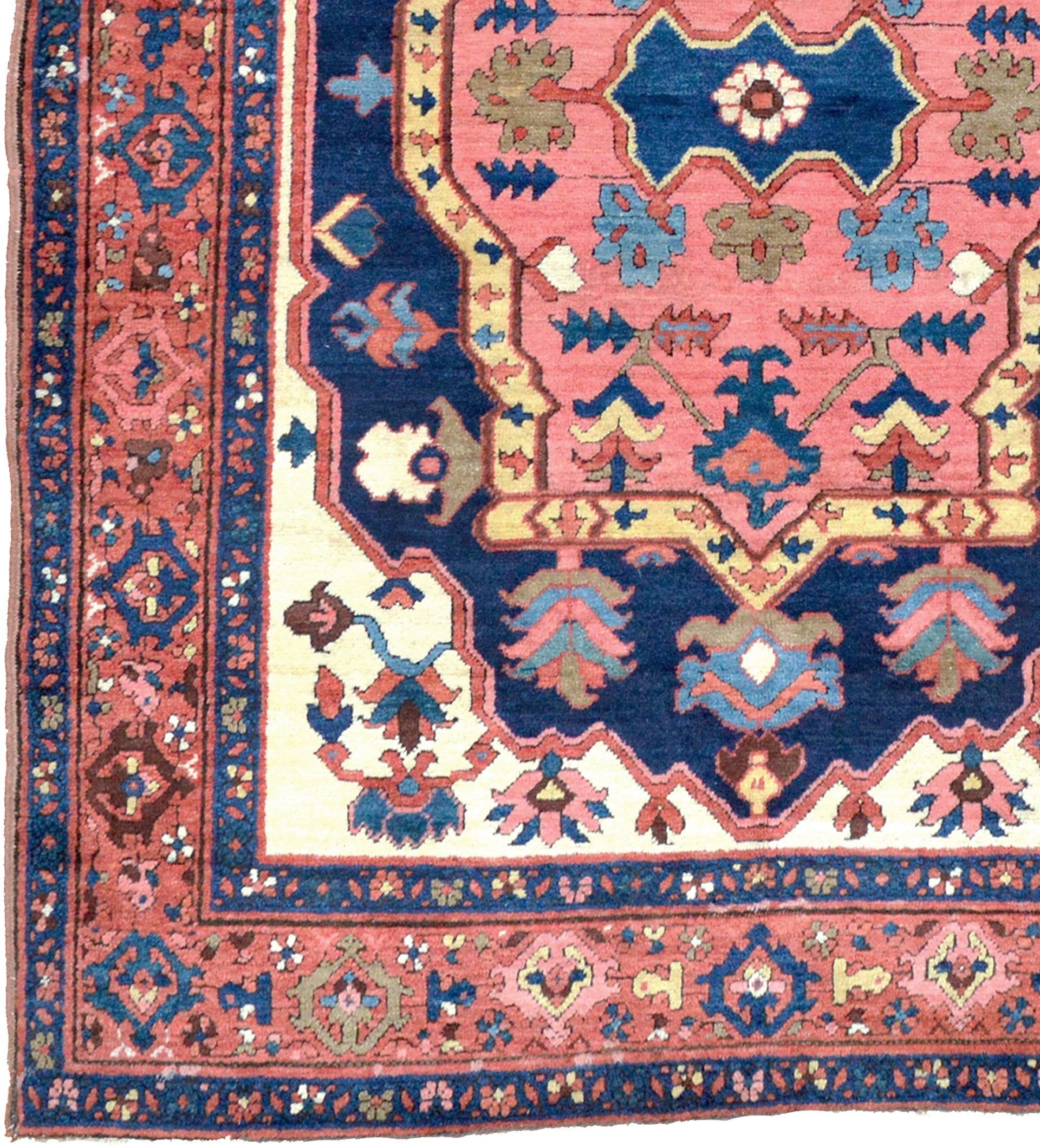 Detail of an antique Persian Bakshaish rug with a coral medallion, navy field, ivory spandrels and a brick red border