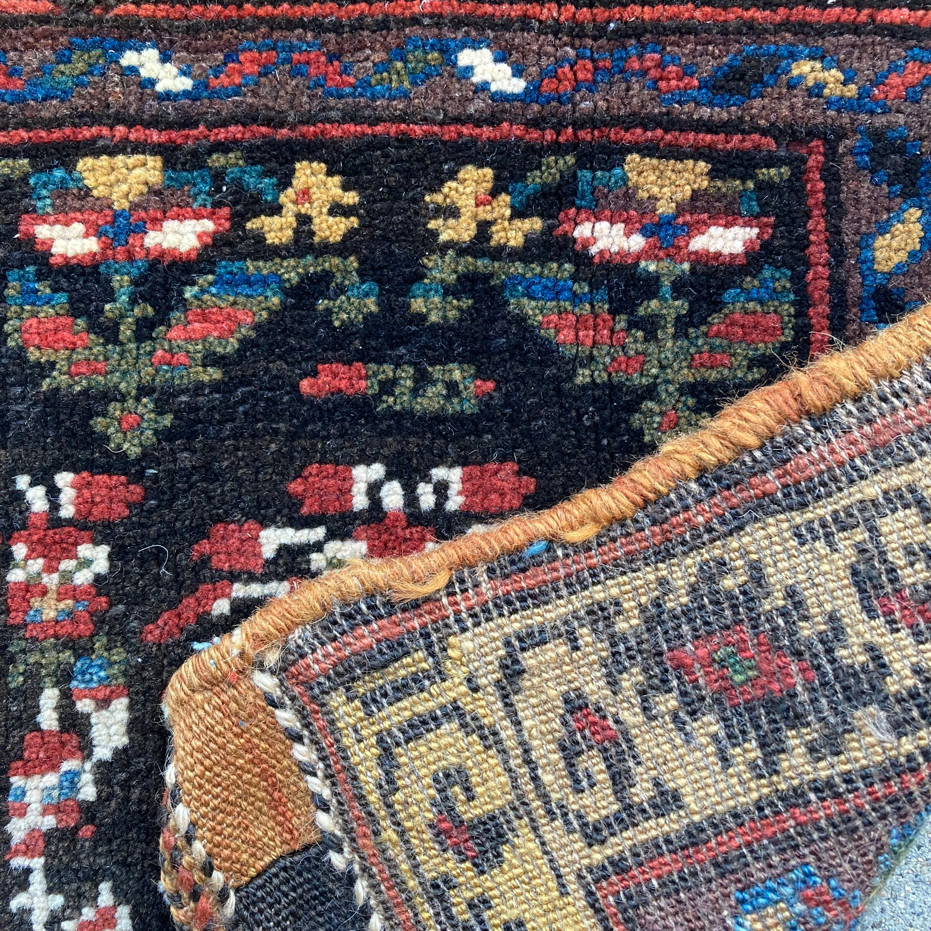 Weave detail from an antique northwest Persian Kurdish bag face with stylized flowers on a deep brown field that is framed by an aubergine color minor border and a pale yellow / camel color major border. Douglas Stock Gallery, antique tribal rugs, antique tribal bags, antique tribal bag face, Kurdish bags, Kurdish bag faces