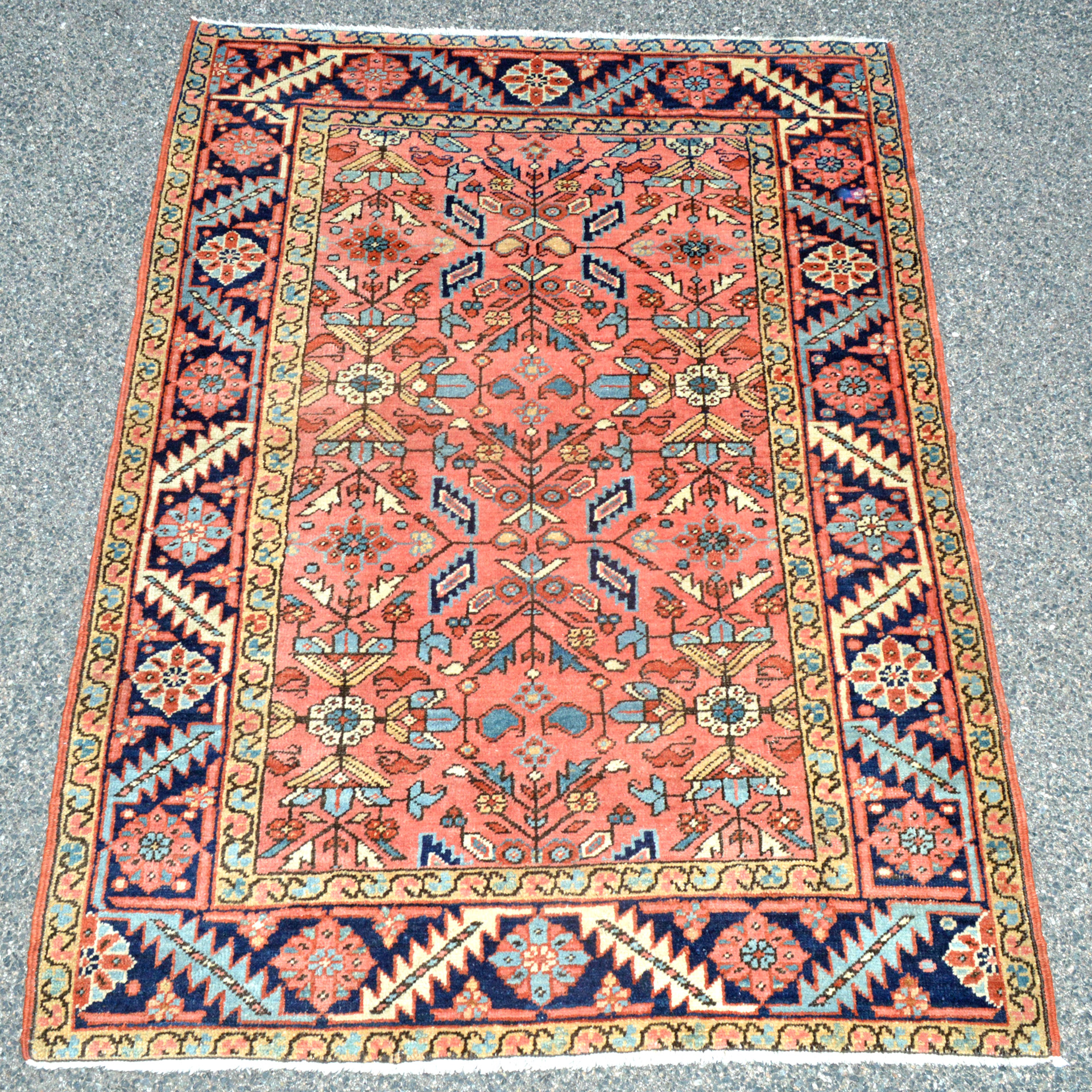 Douglas Stock Gallery, antique Oriental rugs South Natick, Massachusetts New England, an antique Persian Heriz rug with an uncommon coral color field and an all-over design of stylized leaves and flowers that is framed by a navy blue border, circa 1920.