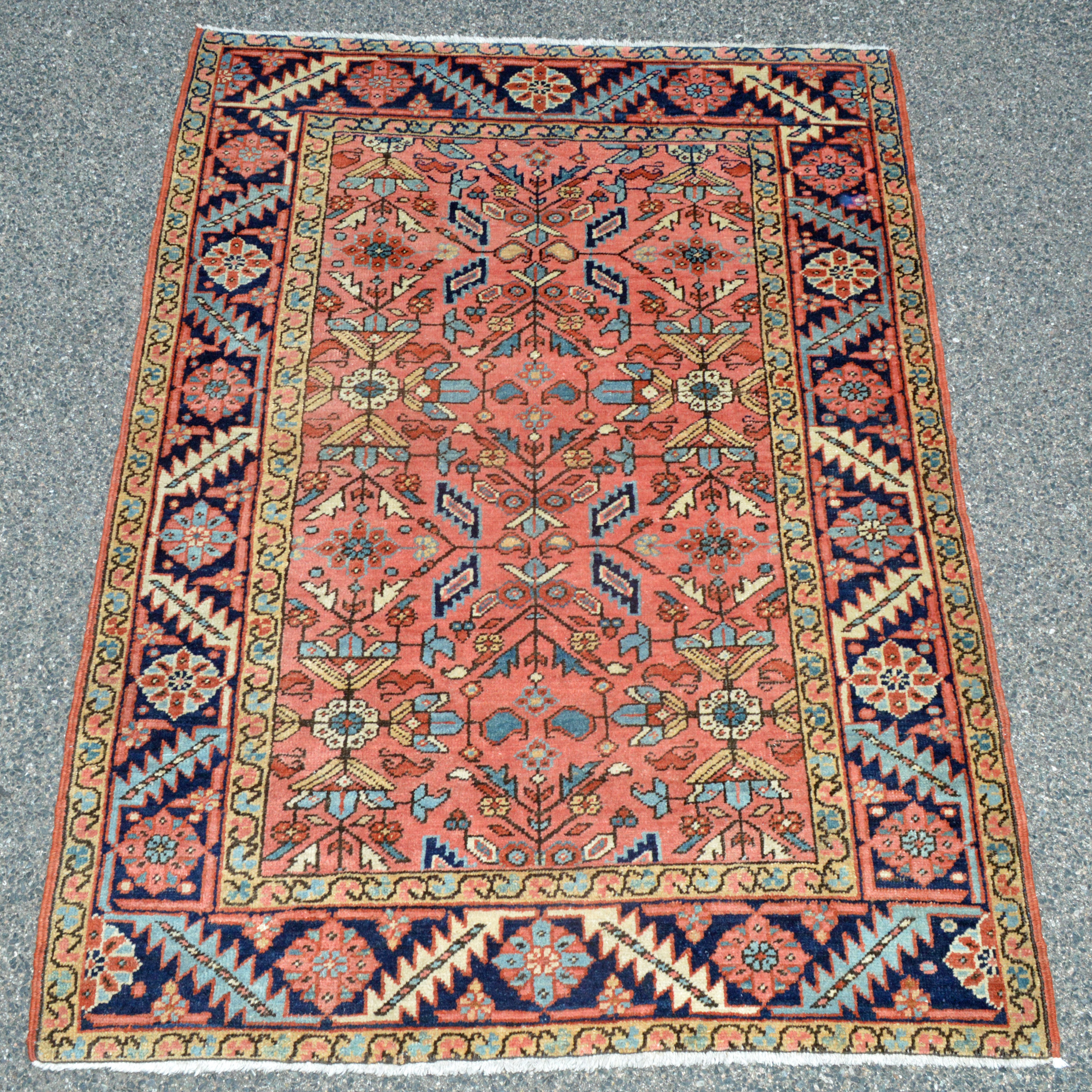 Antique Persian Heriz rug with an uncommon coral color field decorated with stylized leaves and flowers and framed by a navy blue border - Douglas Stock Gallery, antique Oriental rugs Boston,MA area