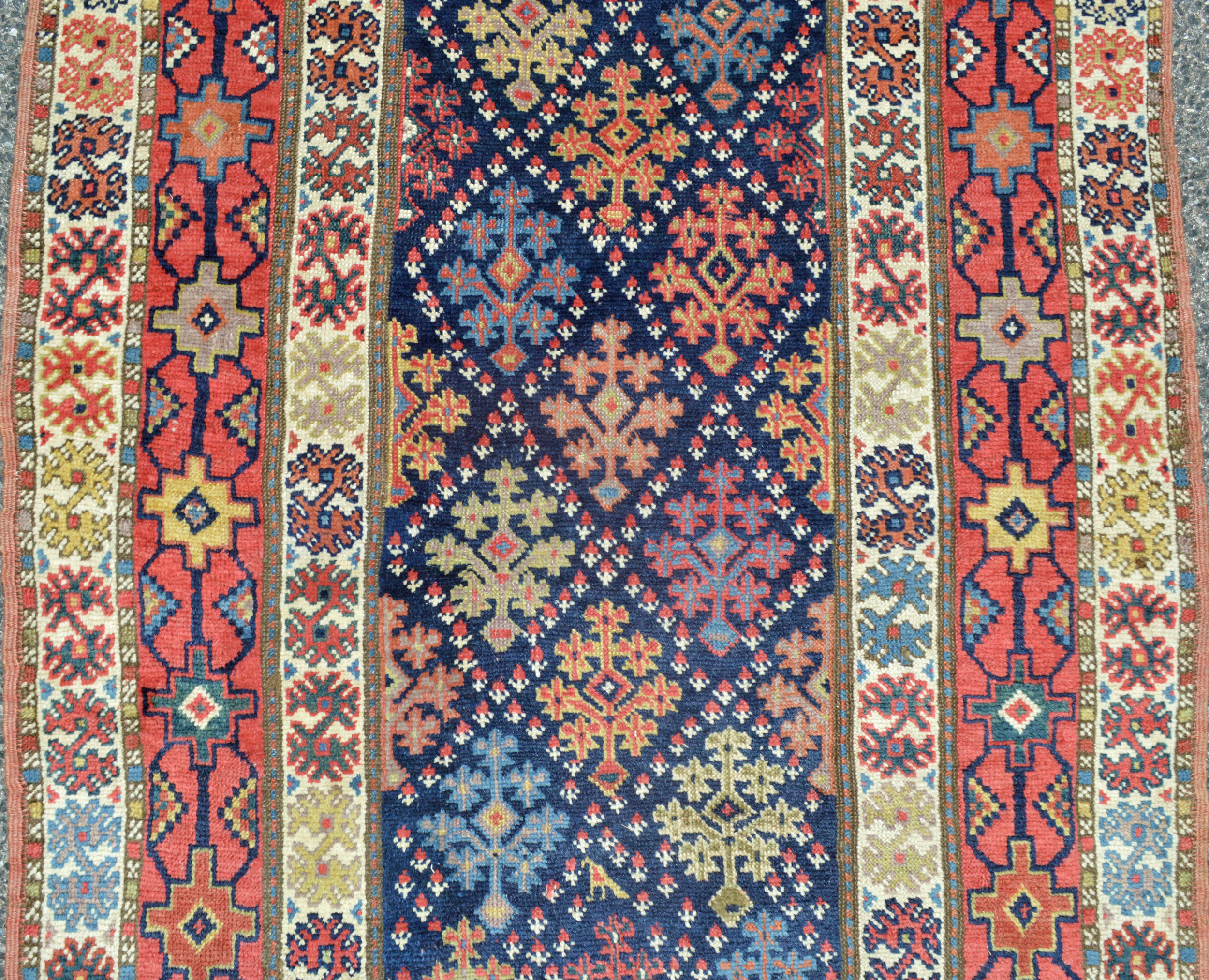 Detail of an antique Oriental runner rug with a stylized lattice and shrub design on a navy field that is framed by a red, geometric design border, Douglas Stock Gallery, antique Oriental runners, antique runner rugs Boston,MA area