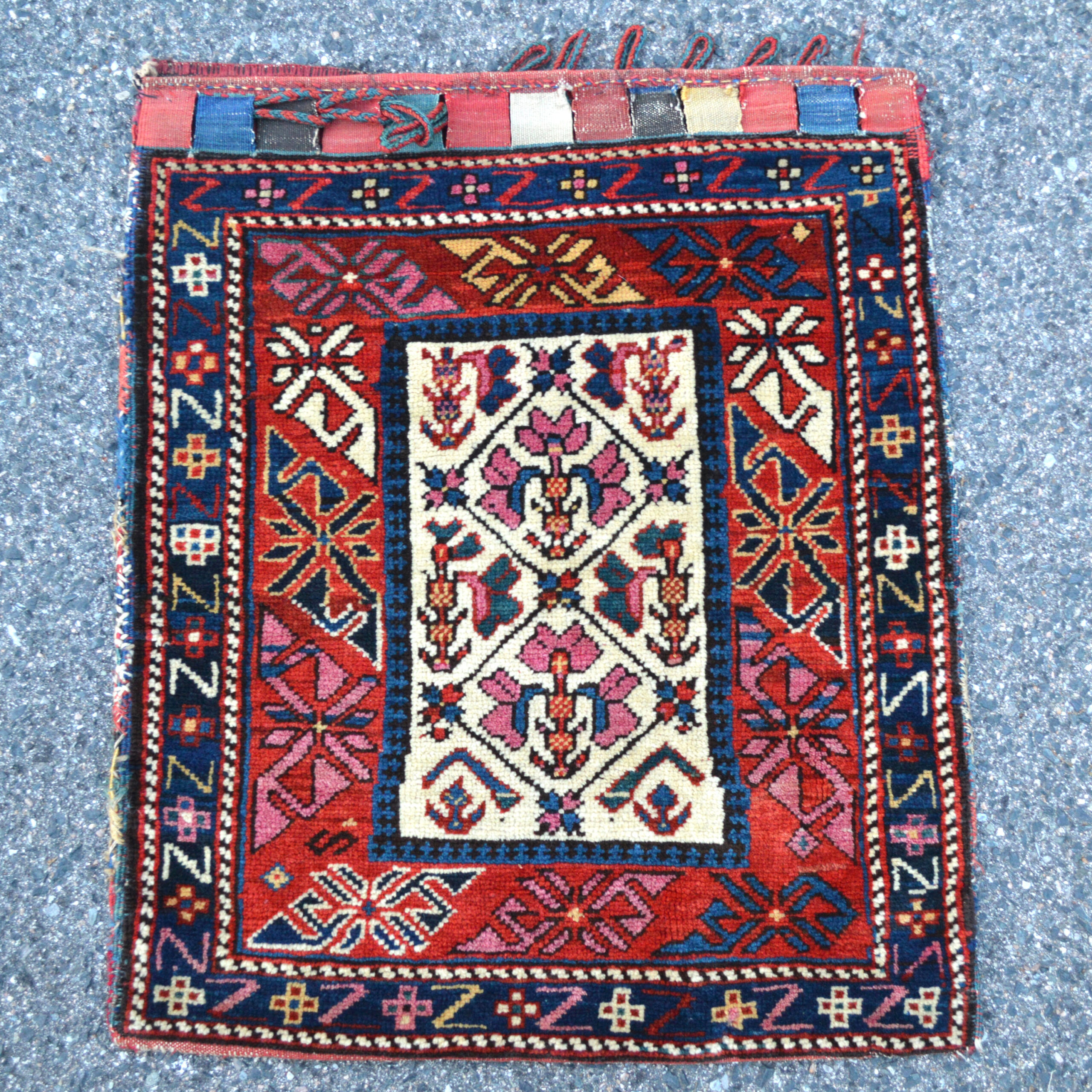 Douglas Stock Gallery, antique Persian and Caucasian tribal bags, antique bag faces - An antique south Caucasian bag with an ivory field that is decorated with stylized flowers using a cochineal dye. A red major border and navy border frame the field. This antique Caucasian bag retains its original closure tabs and beautiful, polychromatic striped kilim (flat woven) back - Antique rugs Boston,MA area New England, NYC, collector rugs and bags, antique rugs and bags for sophisticated collectors