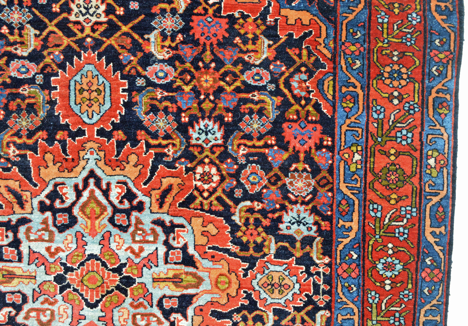 Detail of the sky blue and red medallion on a navy blue "Herati" design field from an antique Persian Bidjar rug. A red border with a scrolling vine and flower design and mid blue guard borders frame the field - Douglas Stock Gallery, antique Oriental rugs Boston,MA area