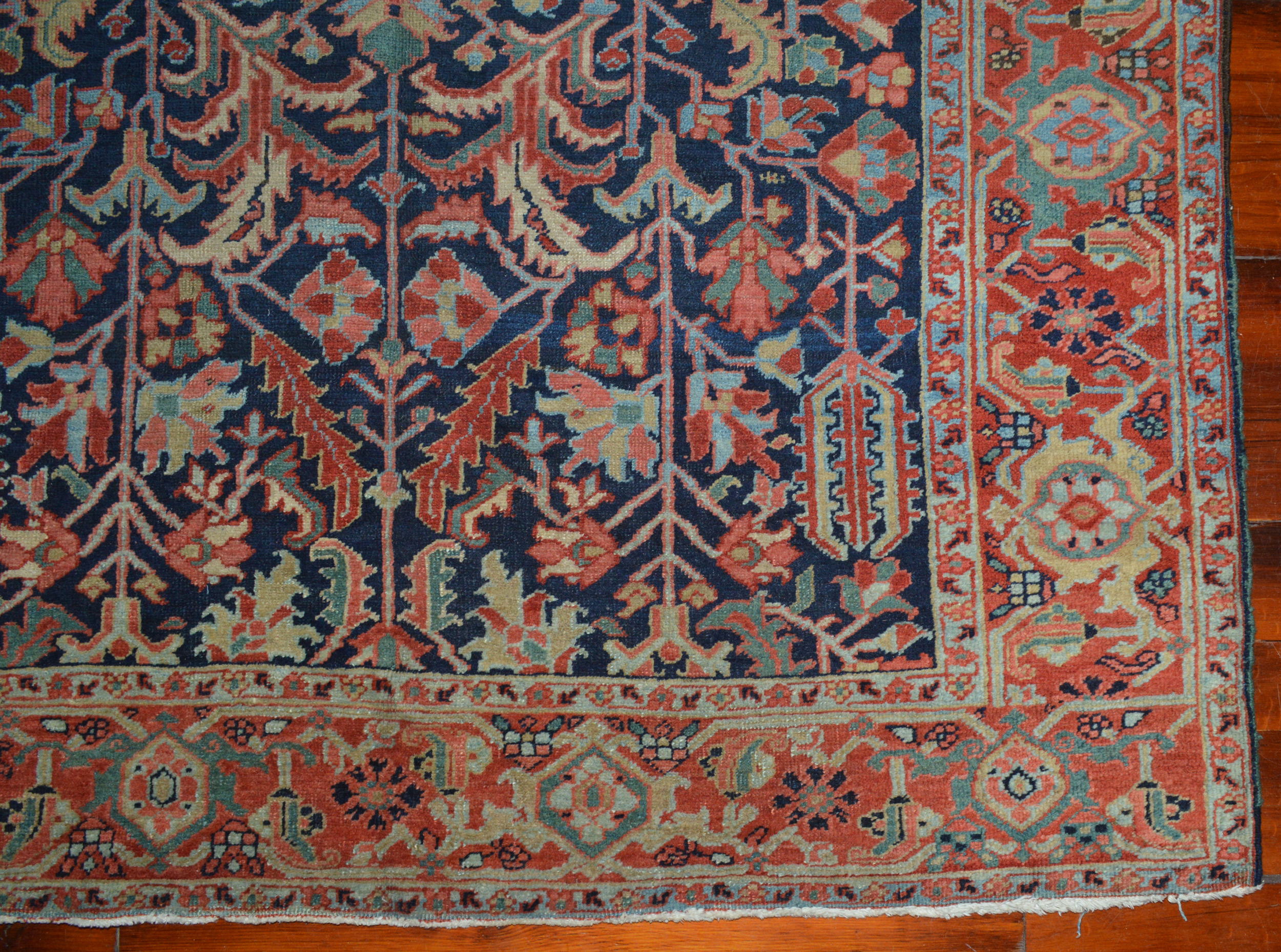 Detail photo of the field and border of an antique Persian Heriz carpet featuring a navy blue field with stylized leaves and flowers. A red border with the Turtle design frames the field. Douglas Stock Gallery, antique Persian carpets and Oriental rugs Boston,MA area