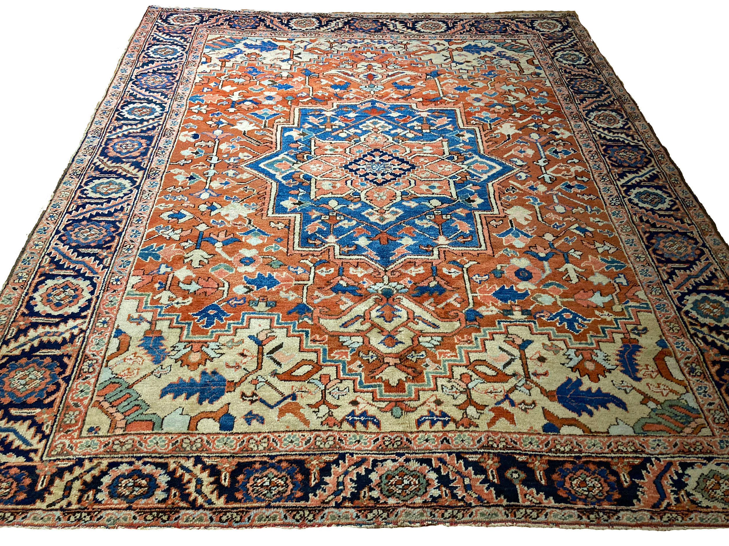 An antique Heriz district carpet from northwest Persia, probably woven in the village of Goravan, circa 1920. The terra cotta color field contains a denim blue and coral medallion and is decorated with stylized floral forms. Light camel color spandrels and a navy blue border frame the field. Douglas Stock Gallery, antique rugs Boston,MA area