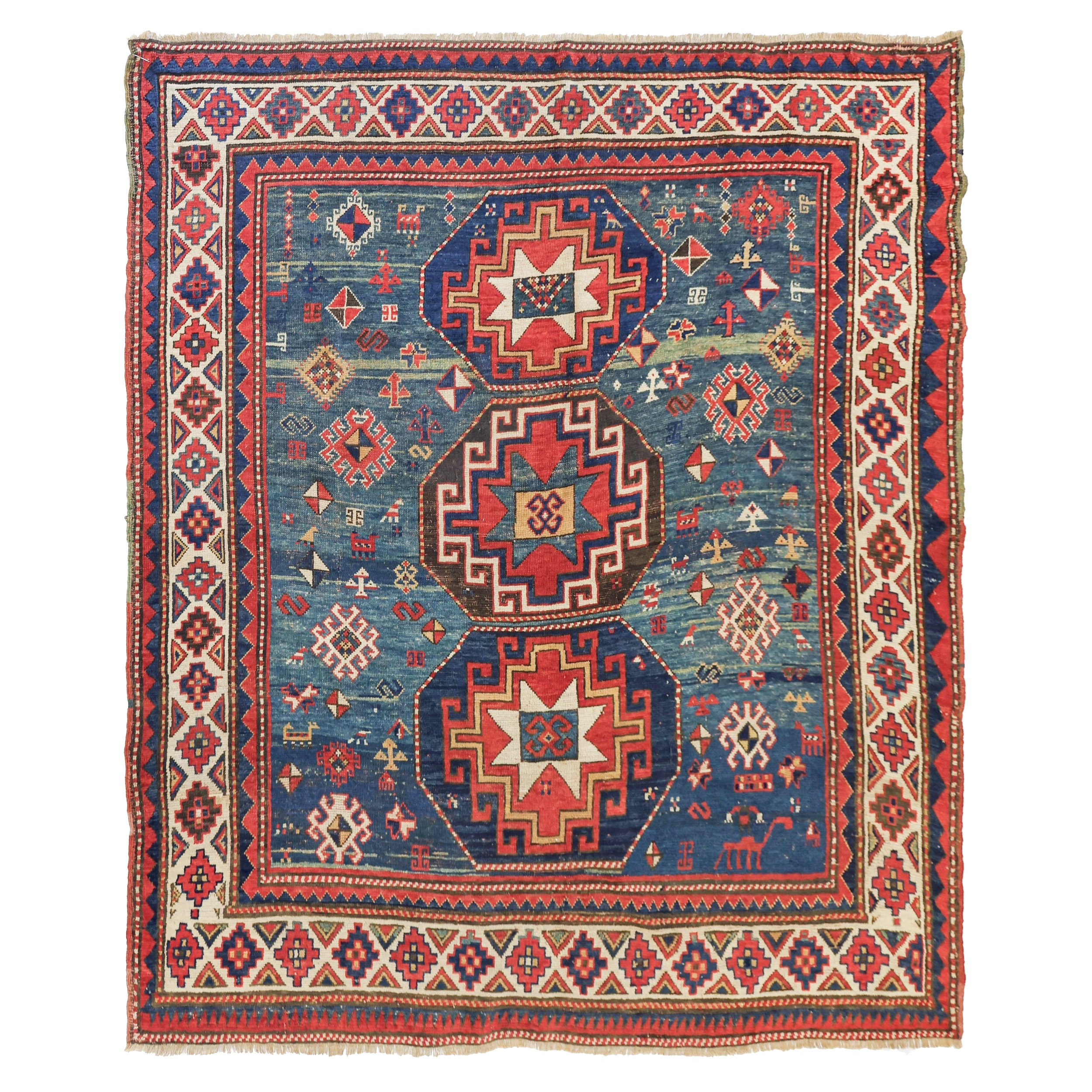 An early antique Caucasian Kazak rug with three Memling Guls on an abrashed blue green field, probably 3rd quarter of the 19th century.