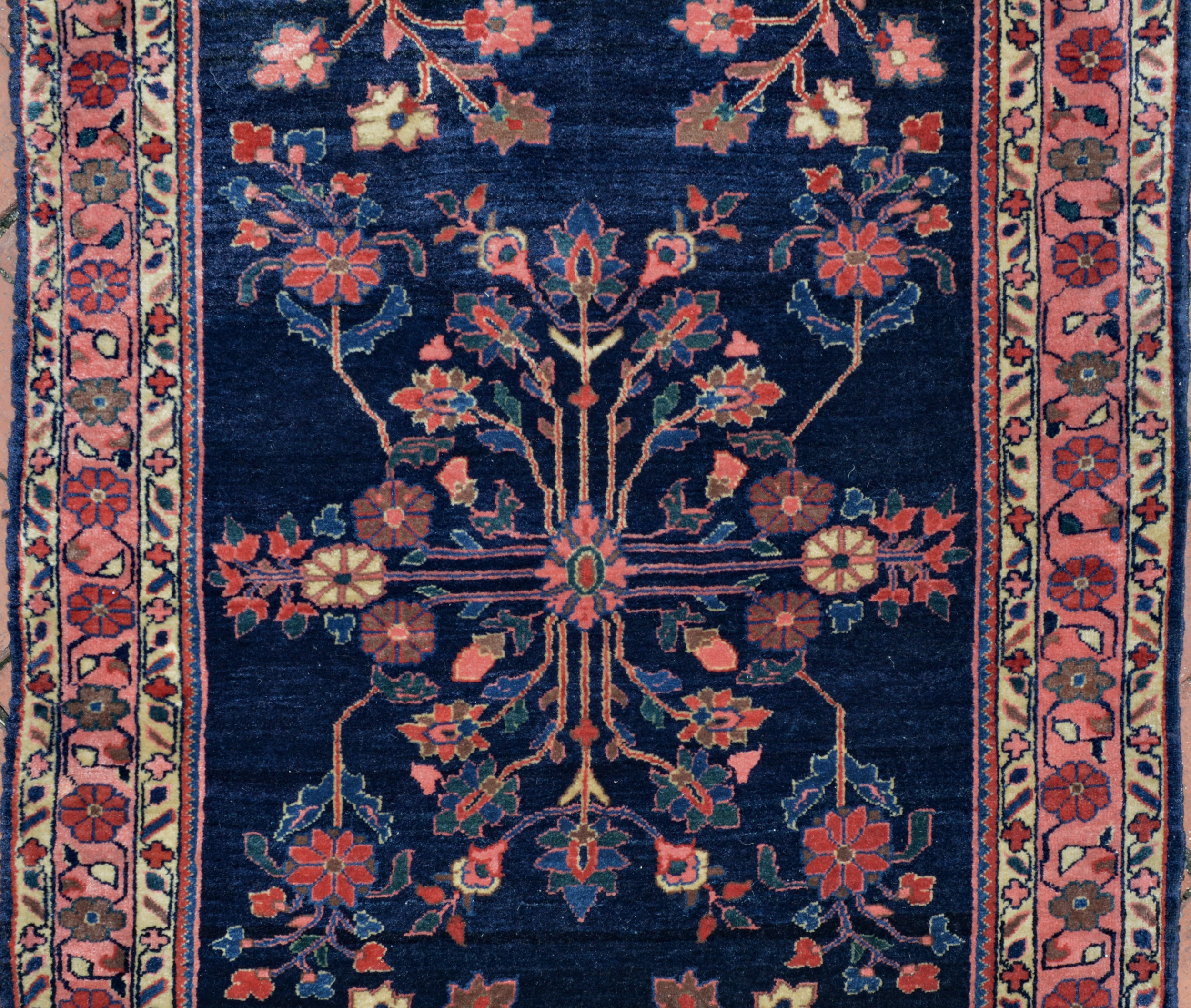 Field detail from a finely woven antique Persian Mahajaran Sarouk rug. The navy field is decorated with stylized floral forms and framed by a coral border with ivory guard borders. Douglas Stock Gallery is one of America's most selective dealers in antique Oriental rugs and specializes in antique Persian Fereghan Sarouk rugs and Mahajaran Sarouk rugs.
