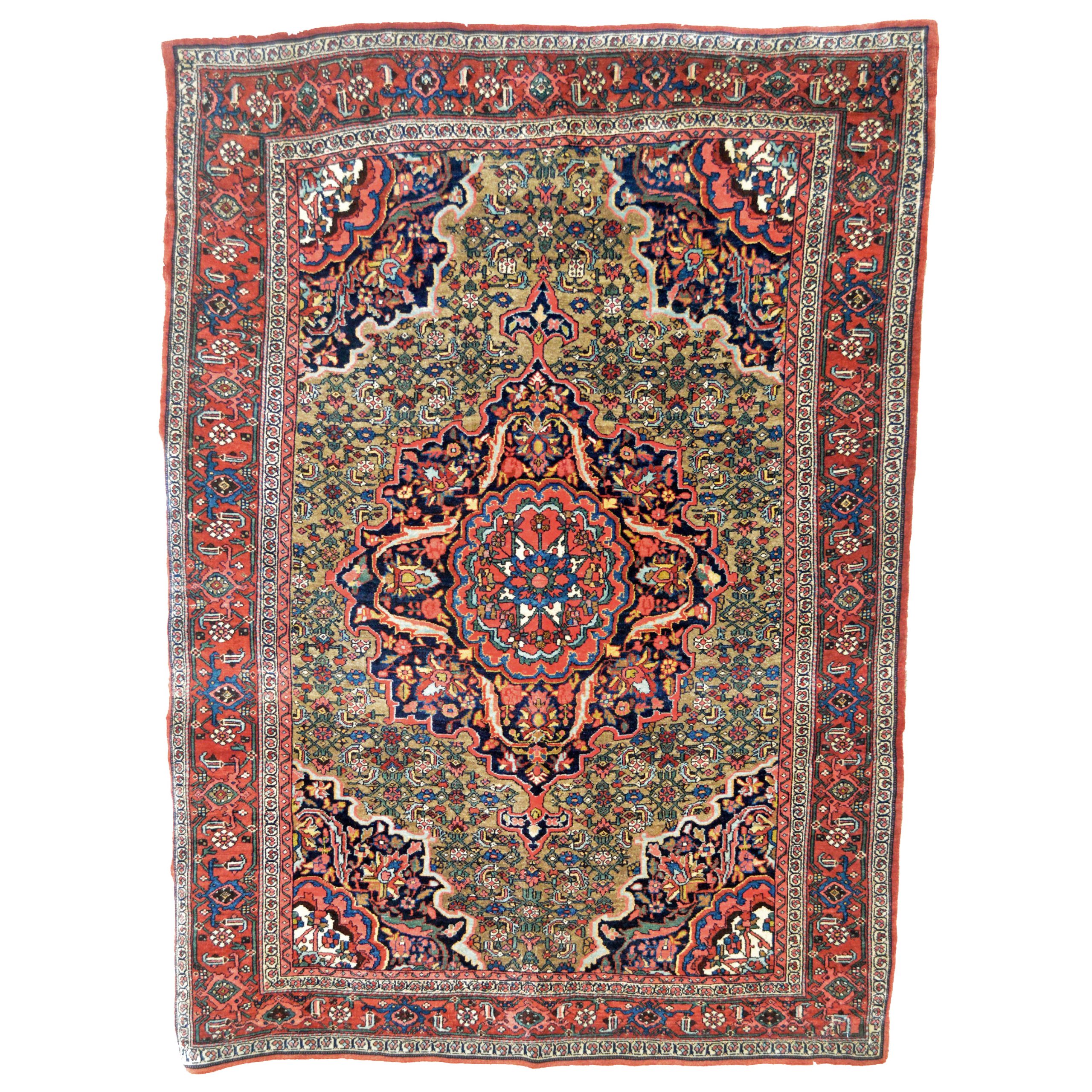 An antique Persian Bidjar with a camel color field that is decorated with a navy blue and coral medallion and the classical "Herati" design. A red border frames the field.