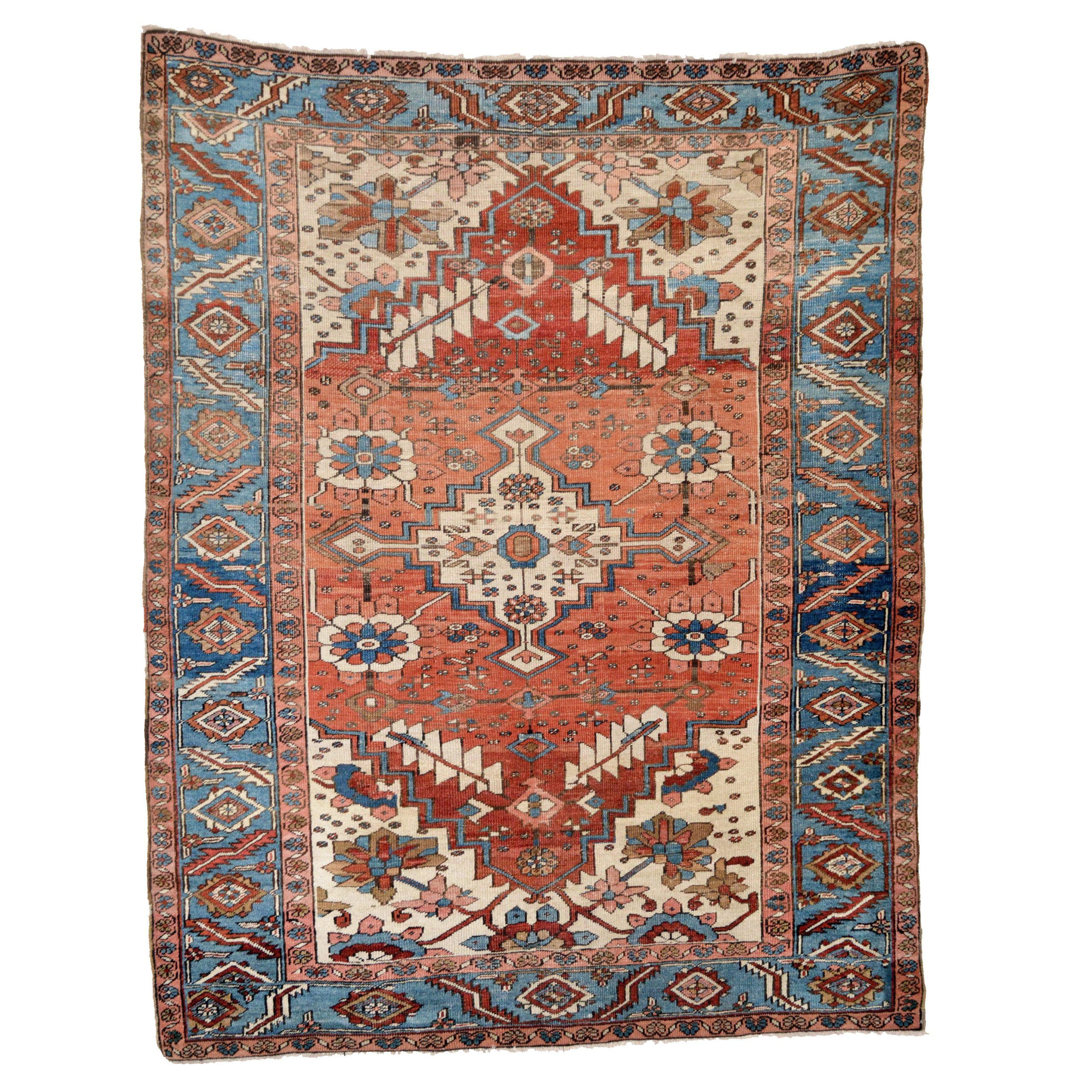 This antique Heriz area rug has some distinctive features: it features a version of the Mina Hani design with a flower and lattice format; it is slightly larger than typical Heriz scatter rugs; and it has a beautiful light blue border. The "abrashed" (variegated) salmon-terra cotta color field contains an ivory medallion and is framed by ivory corner spandrels and a light blue border, northwest Persia, circa 1895 - Douglas Stock Gallery, antique Persian rugs