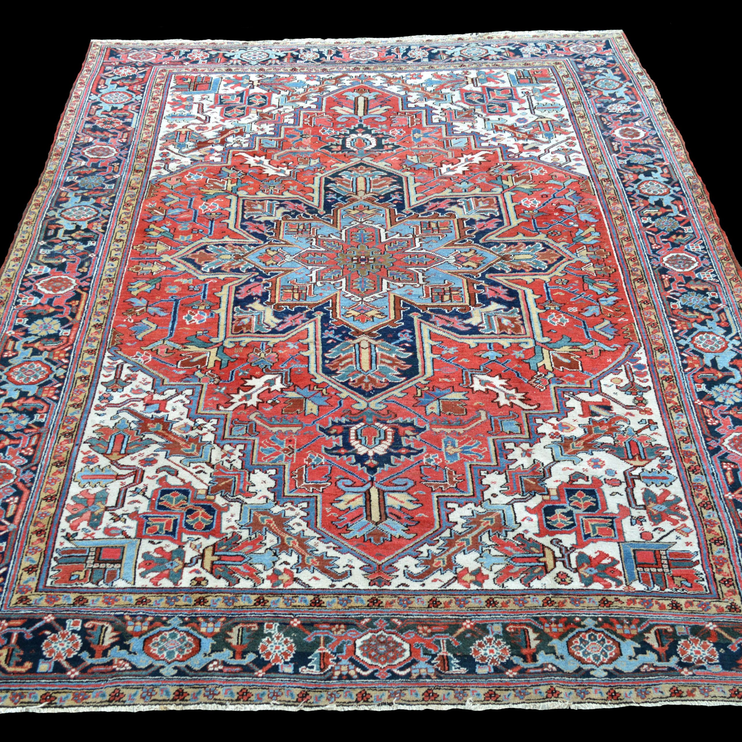 A moderately priced antique Heriz carpet with a navy and light blue medallion on a deep salmon color field that is framed by ivory corner spandrels and a navy blue turtle border, northwest Persia, circa 1925, Douglas Stock Gallery, antique Heriz carpets Boston,MA area New England
