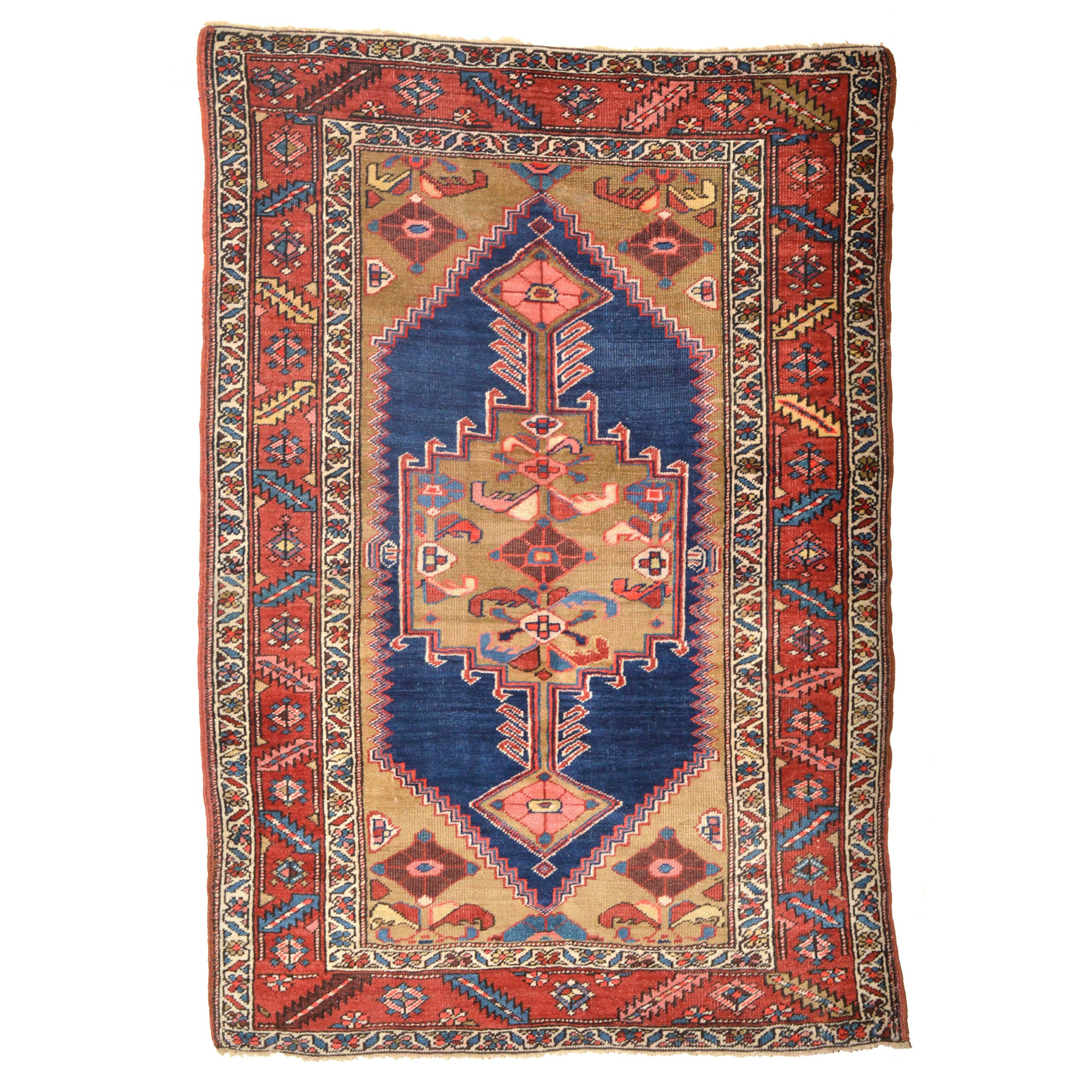 An antique Heriz rug with a navy blue open field decorated with a camel color medallion. Camel color corner spandrels and a bric red border with ivory guard borders frame the field, northwest Persia, circa 1920. Douglas Stock Gallery antique Persian rugs Boston,MA area
